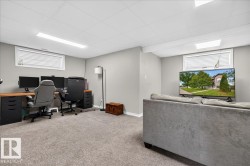 Finished Basement Recreation Area featuring carpeted flooring, recessed and linear ceiling lighting, large windows with cellular blinds, built-in desk workspace with storage cabinetry, and a comfortable seating zone with upholstered sectional sofa - 