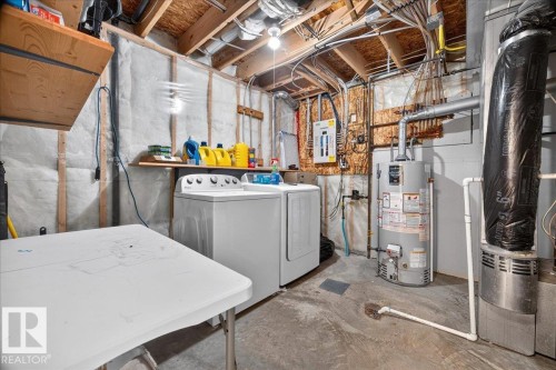 Utility space featuring washer and dryer appliances, concrete flooring, exposed wood-beam ceiling, ductwork infrastructure, and shelving for storage and supplies - 887 Oakland Boulevard, Devon, AB - Indoor Photo Showing Laundry Room