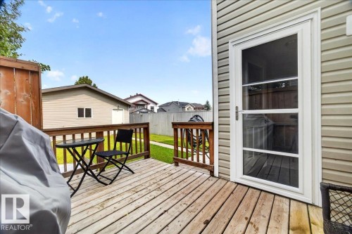 Spacious composite deck with wood-finish flooring and black metal railings, anchored by a glass sliding door with multiple panes - 887 Oakland Boulevard, Devon, AB - Outdoor With Exterior