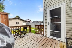 Spacious composite deck with wood-finish flooring and black metal railings, anchored by a glass sliding door with multiple panes - 