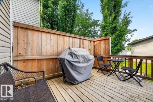 Spacious composite deck featuring multiple entertaining zones with wood-finish decking, custom wooden privacy fencing, and mature landscaping providing natural screening - 887 Oakland Boulevard, Devon, AB - Outdoor With Deck Patio Veranda With Exterior