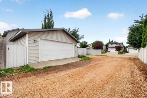 Detached garage with horizontal siding, a white garage door, and a gravel driveway - 887 Oakland Boulevard, Devon, AB - Outdoor
