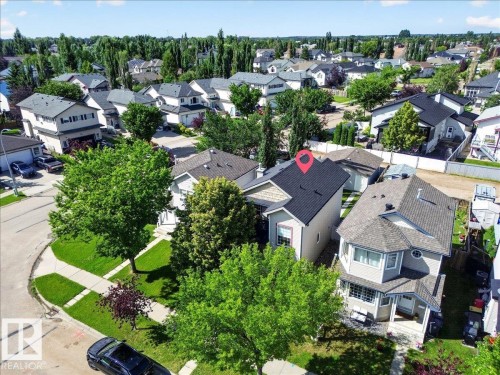 Aerial view showcasing a two-story residence with a dark asphalt shingle roof, situated on a manicured lot with mature landscaping - 887 Oakland Boulevard, Devon, AB - Outdoor