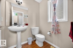 Pedestal sink with chrome faucet, large mirror, and wood-finish flooring - 