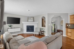 Living area featuring wood-finish flooring, a white brick fireplace with a mantel, and a built-in media cabinet - 