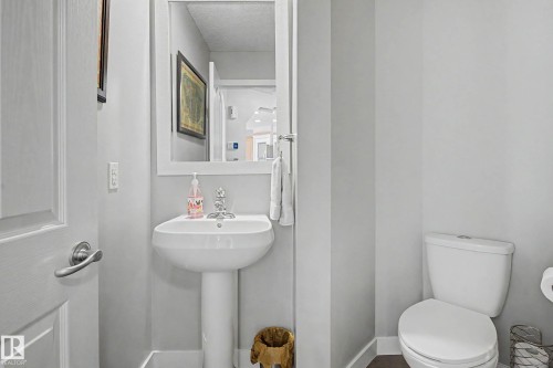 Pedestal sink with chrome faucet, framed mirror, and white toilet - 21 Nash Close, St. Albert, AB - Indoor Photo Showing Bathroom