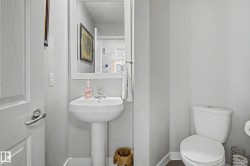 Pedestal sink with chrome faucet, framed mirror, and white toilet - 