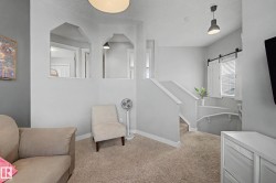 Carpeted upper landing featuring a pendant light fixture, a staircase with white railings, and a window with a barn door style shutter and blinds - 