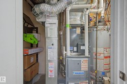 Utility closet featuring a water heater, furnace, and exposed ductwork - 