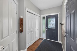 Entryway featuring a dark paneled door with decorative glass, frosted sidelight, and wood-finish flooring - 