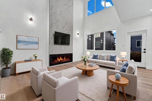 Soaring ceilings with upper windows, a floor-to-ceiling fireplace with stone-look surround, and wood-finish flooring - 4303 36 Street, Beaumont, AB - Indoor Photo Showing Living Room With Fireplace