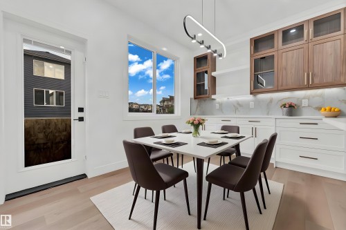 White shaker lower cabinetry, wood-finish upper cabinetry, light wood-finish flooring, white countertop, and a contemporary linear light fixture - 4303 36 Street, Beaumont, AB - Indoor Photo Showing Dining Room