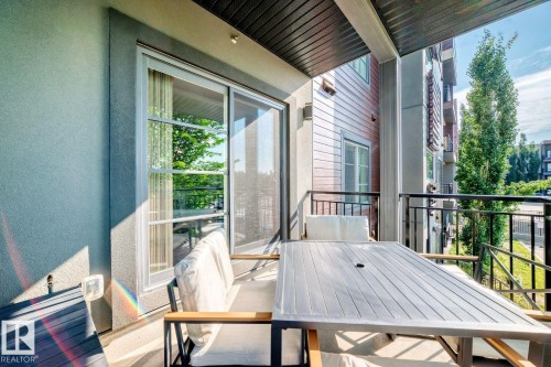 Private balcony featuring a sliding glass door, textured exterior wall, and dark-finish railings - #238 1008 Rosenthal Bv Nw, Edmonton, AB - Outdoor With Exterior