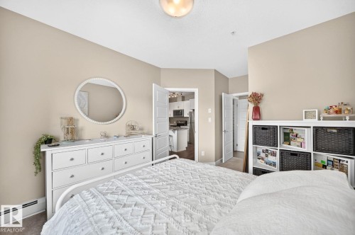 Neutral wall tones, overhead light fixture, white baseboards, and wood-finish flooring - #238 1008 Rosenthal Bv Nw, Edmonton, AB - Indoor Photo Showing Bedroom