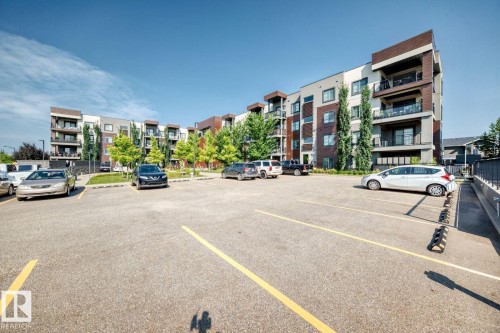 Contemporary multifamily building with individual balconies, prominent window features, and a communal parking area - #238 1008 Rosenthal Bv Nw, Edmonton, AB - Outdoor With Balcony With Facade