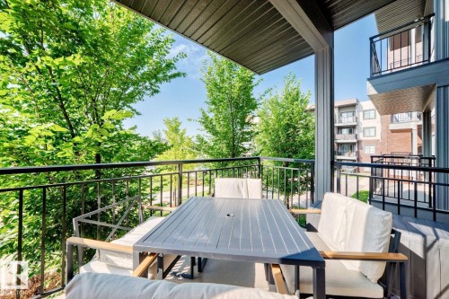 Outdoor covered balcony featuring a black metal railing and a slatted ceiling - #238 1008 Rosenthal Bv Nw, Edmonton, AB - Outdoor With Balcony With Exterior