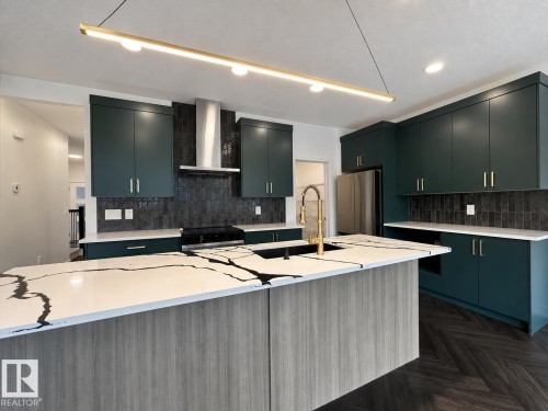 Modern kitchen featuring a large central island with a waterfall-edge countertop and integrated sink - 5478 Kootook Road Sw, Edmonton, AB - Indoor Photo Showing Kitchen With Upgraded Kitchen