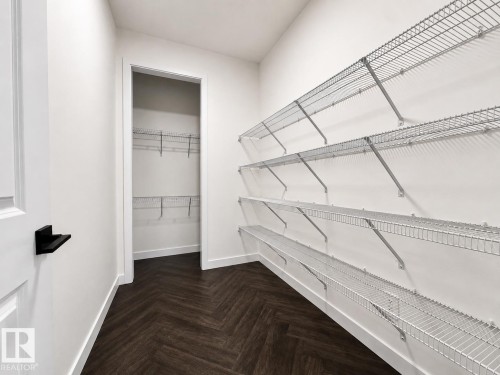 Spacious walk-in closet featuring extensive wire shelving, a herringbone wood-finish floor, and white trim - 5478 Kootook Road Sw, Edmonton, AB - Indoor