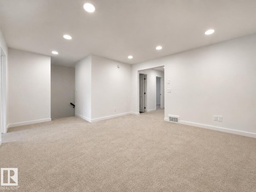 Spacious room featuring neutral carpeting, recessed ceiling lighting, and clean white walls - 5478 Kootook Road Sw, Edmonton, AB - Indoor
