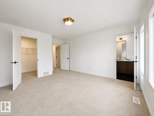 Bright room featuring light-toned carpeting, white walls, and a modern brass ceiling fixture - 5478 Kootook Road Sw, Edmonton, AB - Indoor Photo Showing Other Room