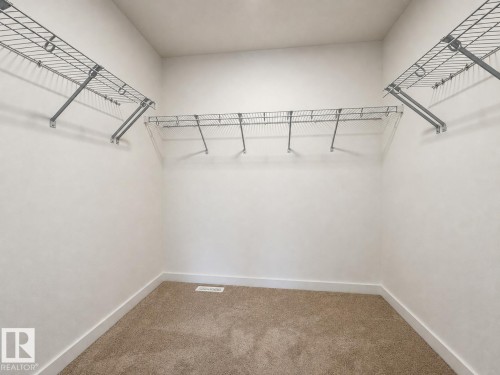 Walk-in closet featuring wire shelving, white walls, white baseboards, and tan carpet flooring - 5478 Kootook Road Sw, Edmonton, AB - Indoor With Storage