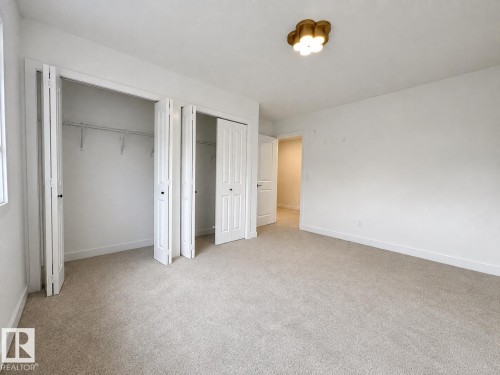 Spacious room featuring neutral carpeting, white painted walls, and a contemporary ceiling light fixture - 5478 Kootook Road Sw, Edmonton, AB - Indoor Photo Showing Other Room