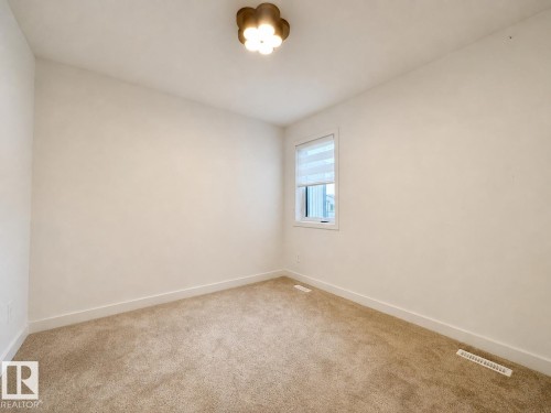 Carpeted room featuring a single window with blinds, white baseboards, and a contemporary ceiling light fixture - 5478 Kootook Road Sw, Edmonton, AB - Indoor Photo Showing Other Room