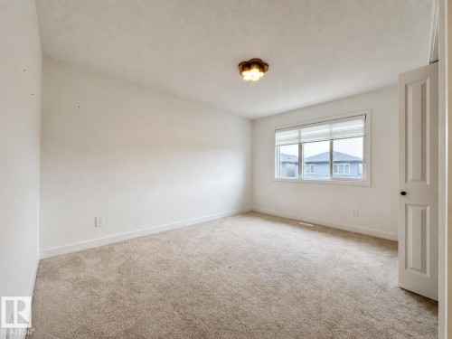 Bright room featuring a large window with horizontal blinds, neutral carpeting, and white baseboards - 5478 Kootook Road Sw, Edmonton, AB - Indoor Photo Showing Other Room