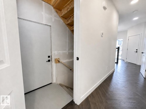 Herringbone-patterned wood-finish flooring in a bright hallway with recessed lighting - 5478 Kootook Road Sw, Edmonton, AB - Indoor Photo Showing Other Room
