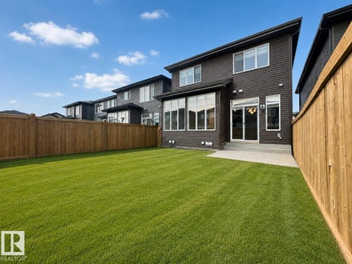 Spacious backyard featuring a large green lawn, full wood privacy fencing, and a concrete patio - 5478 Kootook Road Sw, Edmonton, AB - Outdoor