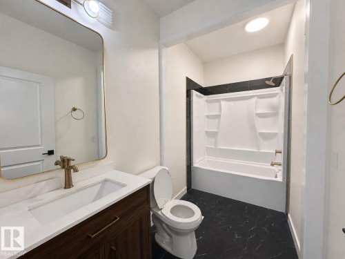 Contemporary bathroom featuring a dark wood-finish vanity with a white countertop and integrated sink - 5478 Kootook Road Sw, Edmonton, AB - Indoor Photo Showing Bathroom