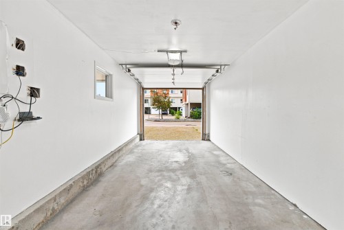 Spacious single-bay garage featuring a concrete floor, freshly painted white walls, and a small window - #144 104 West Haven Dr, Leduc, AB - Indoor