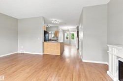 Open-concept living area with wood-finish flooring, a white fireplace surround, and light gray wall finishes - 