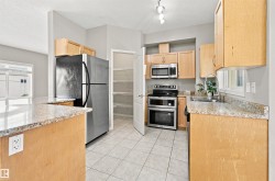 Kitchen featuring light wood-finish cabinetry,  countertops, stainless steel appliances, tile flooring, and a walk-in pantry - 