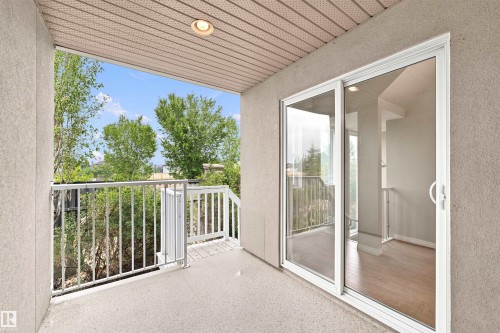 Private balcony featuring a textured stucco exterior, white metal railings, and a wood-finish soffit with recessed lighting - #144 104 West Haven Dr, Leduc, AB - Outdoor With Exterior