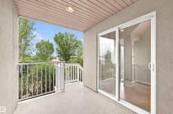 Private balcony featuring a textured stucco exterior, white metal railings, and a wood-finish soffit with recessed lighting - 