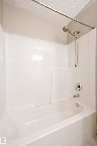 Bathtub and shower combination featuring a white surround, chrome fixtures, and a curved shower rod - #144 104 West Haven Dr, Leduc, AB - Indoor Photo Showing Bathroom