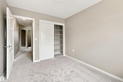 Neutral-toned room featuring light gray carpeting, a built-in closet with sliding doors, and integrated wire shelving - 