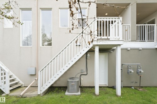 Air Conditioner. Rear exterior featuring an upper-level deck with white railings, direct stair access to the ground level, and a ground-level access door - #144 104 West Haven Dr, Leduc, AB -  Photo Showing Other Room