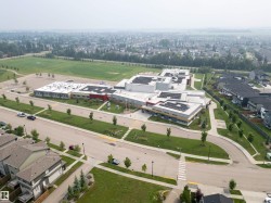 Modern community center featuring extensive solar panel arrays, a large athletic field, and surrounding residential development - 