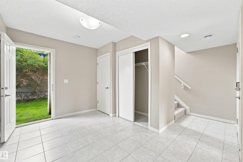 Tiled entryway featuring a double-door exterior access, an interior door, a sliding closet door, and a carpeted staircase - #144 104 West Haven Dr, Leduc, AB - Indoor Photo Showing Other Room