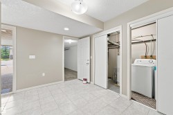 Tiled flooring in a versatile space featuring a built-in laundry area with a top-load washing machine, a utility closet, and a white paneled door - 