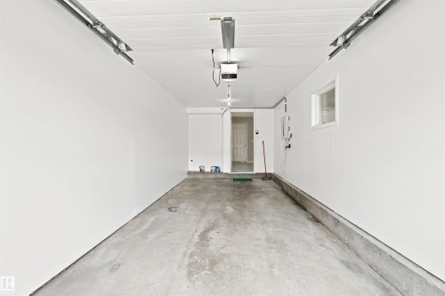 Spacious garage with freshly painted walls, concrete flooring, a window, and an interior access door - #144 104 West Haven Dr, Leduc, AB - Indoor