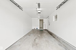 Spacious garage with freshly painted walls, concrete flooring, a window, and an interior access door - 