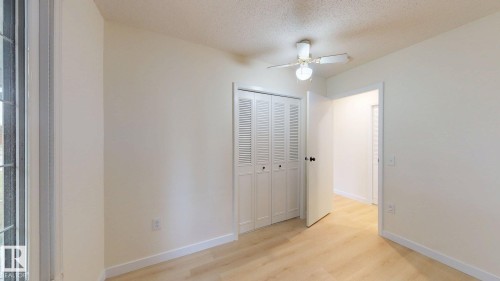 Interior room featuring wood-finish flooring, a ceiling fan with integrated lighting, and a bi-fold louvered closet door - 12812 45 Street Nw, Edmonton, AB - Indoor Photo Showing Other Room