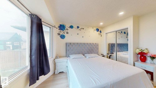 Bright bedroom featuring light wood-finish flooring, a large window, recessed lighting, and mirrored closet doors - 12812 45 Street Nw, Edmonton, AB - Indoor Photo Showing Bedroom