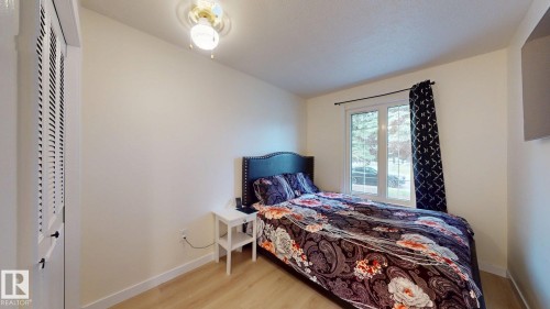 Bedroom featuring light wood-finish flooring, a double-paned window, and a louvered bi-fold closet door - 12812 45 Street Nw, Edmonton, AB - Indoor Photo Showing Bedroom