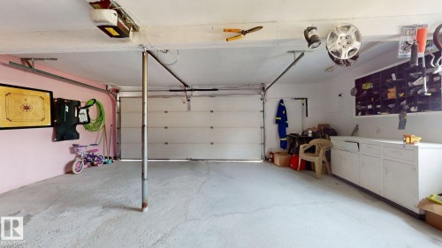 Spacious garage featuring two overhead doors, concrete flooring, built-in cabinetry, and integrated storage solutions - 12812 45 Street Nw, Edmonton, AB - Indoor Photo Showing Garage