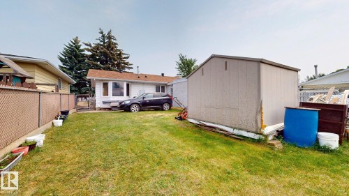 Expansive rear yard featuring green lawn space, a metal storage shed, and a chain-link fence - 12812 45 Street Nw, Edmonton, AB - Outdoor With Exterior