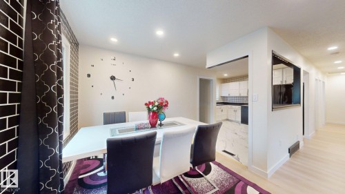 Spacious dining area featuring recessed lighting, a white wall-mounted clock, and a window with dark patterned curtains - 12812 45 Street Nw, Edmonton, AB - Indoor Photo Showing Dining Room